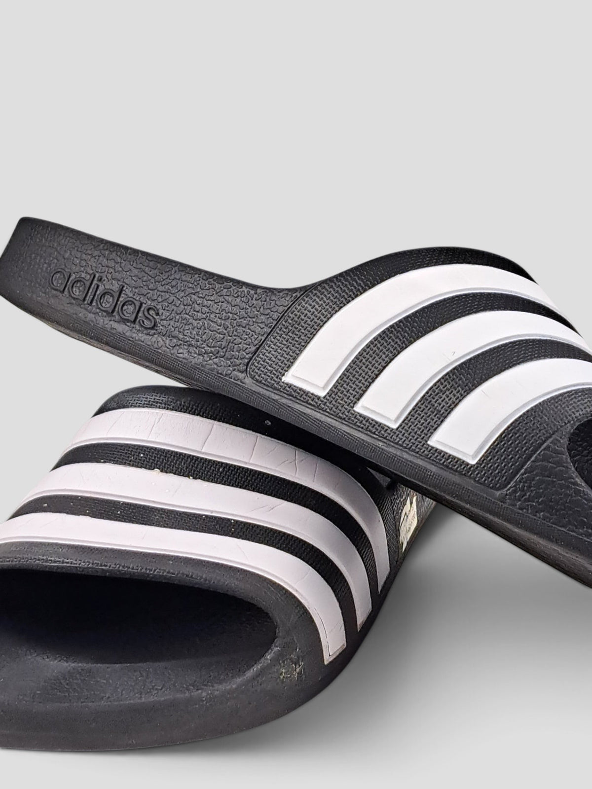 BaraBarnet black Adidas slides with iconic white three-stripe design, made from durable rubber for summer leisure.
