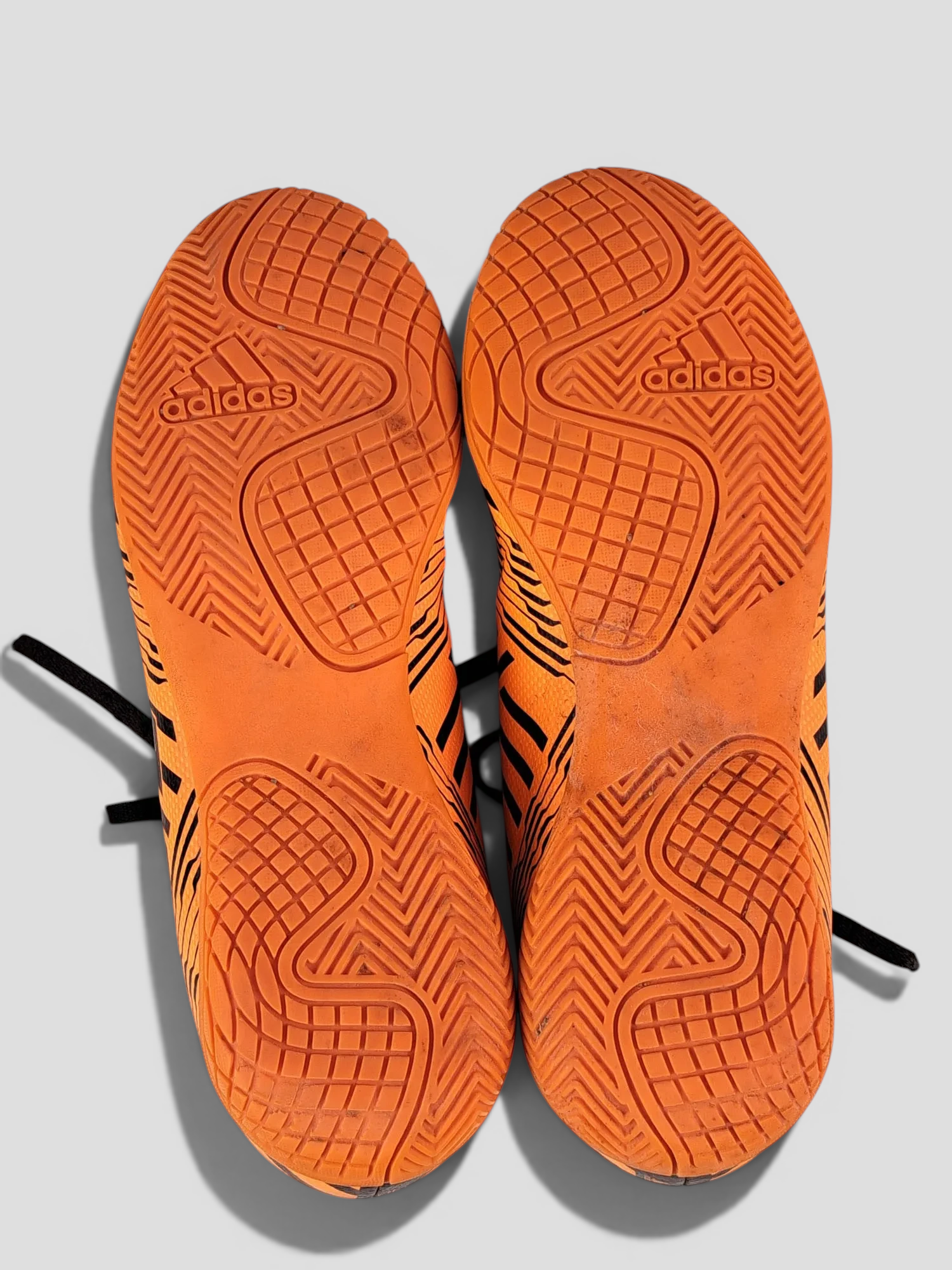 BaraBarnet Adidas indoor soccer shoes featuring bright orange non-marking rubber outsoles with textured grip patterns