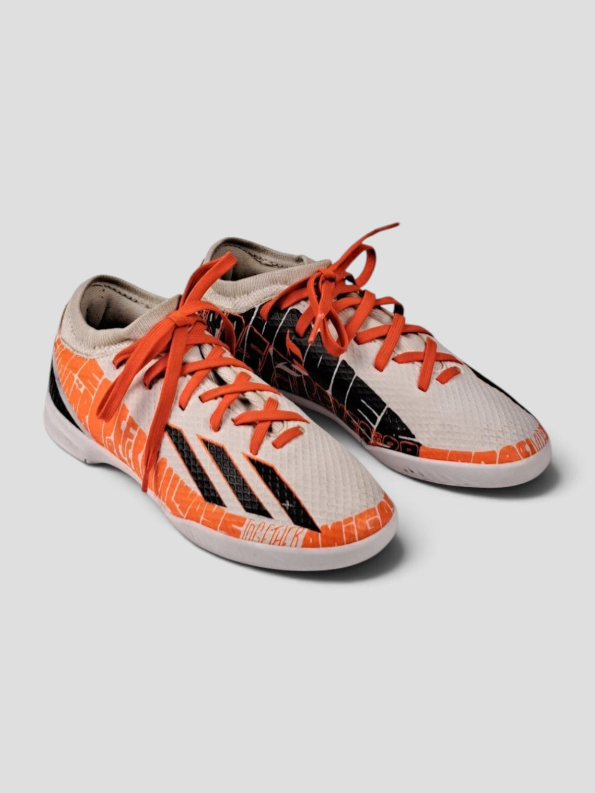 BaraBarnet adidas indoor soccer shoes in white and orange with black graphic details and bright orange laces.
