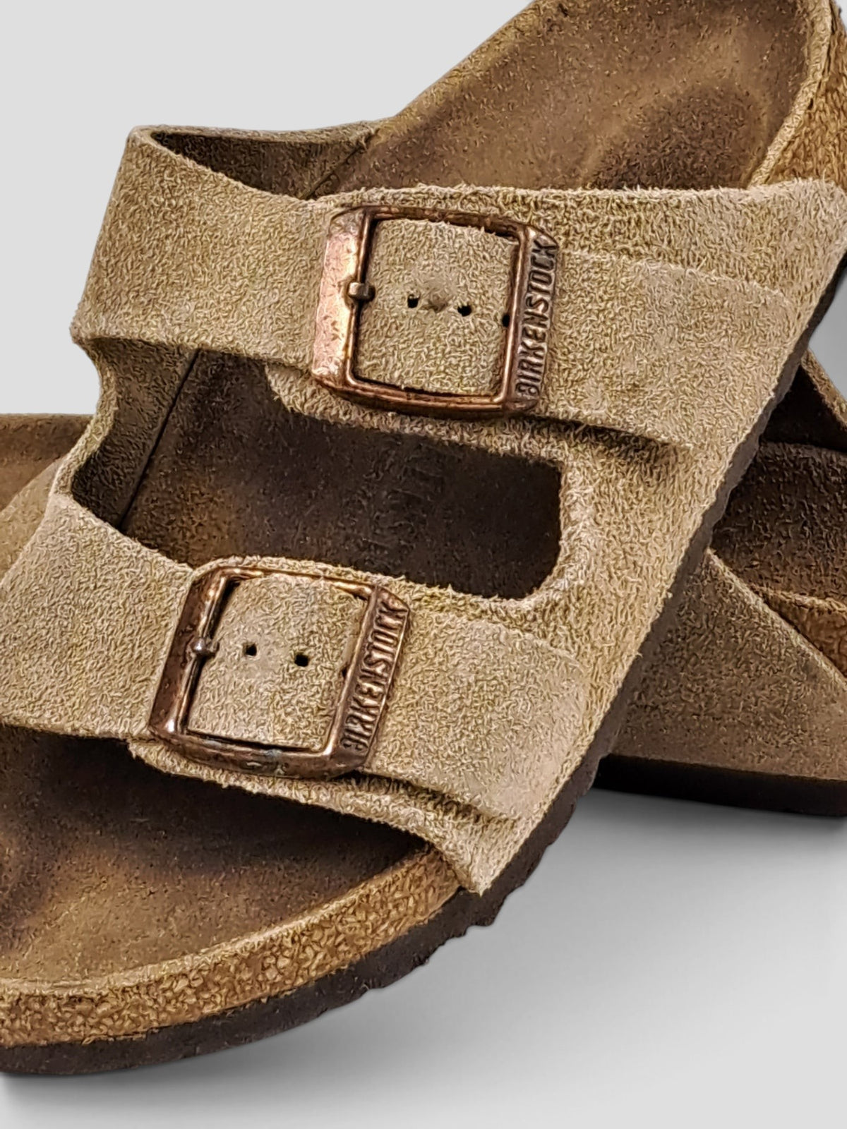 BaraBarnet beige Birkenstock sandals in suede-like material with two adjustable straps and metal buckles.