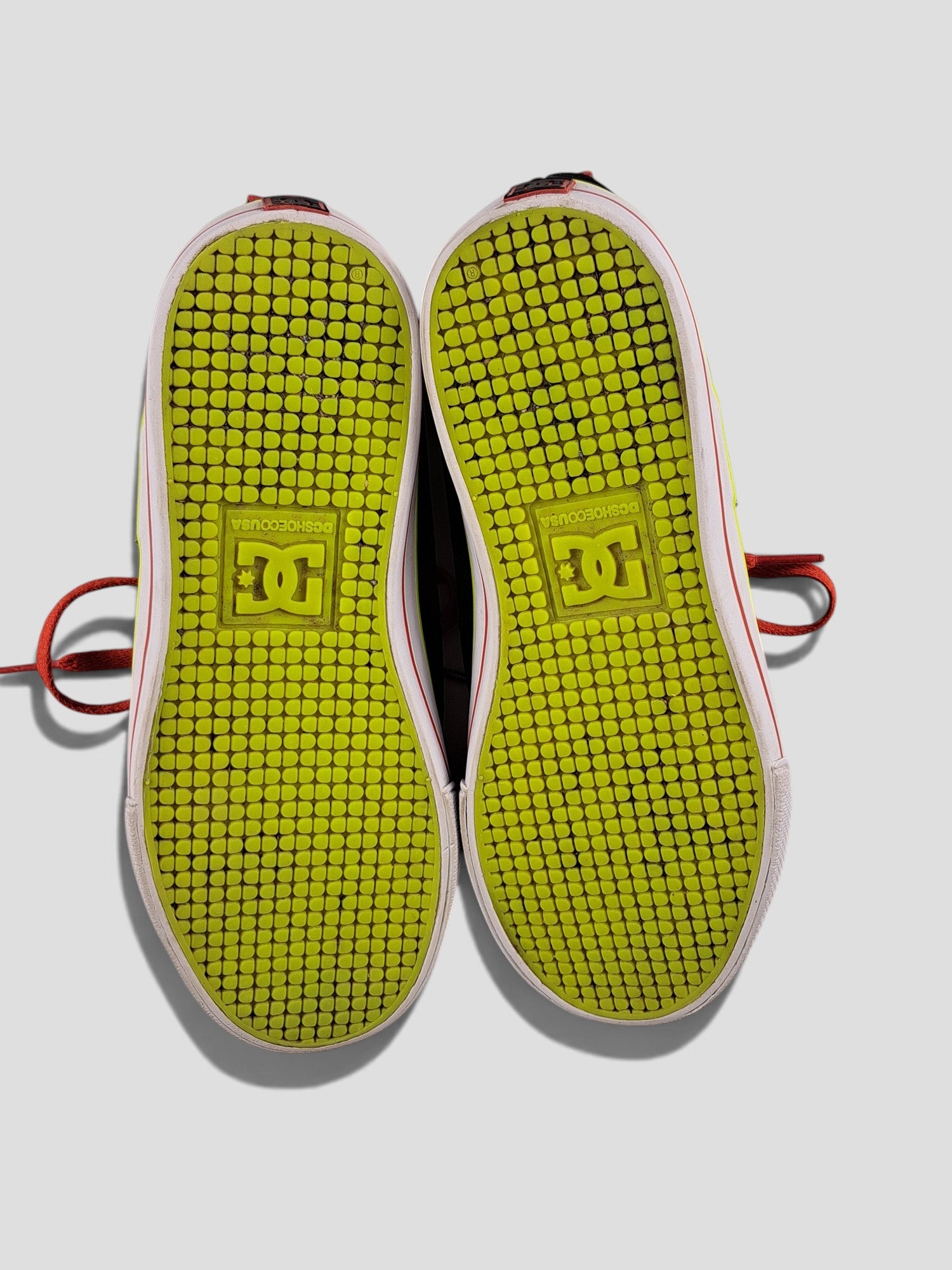 BaraBarnet DcshoecoUSA sneakers with bright lime green patterned rubber soles and red laces on a white background