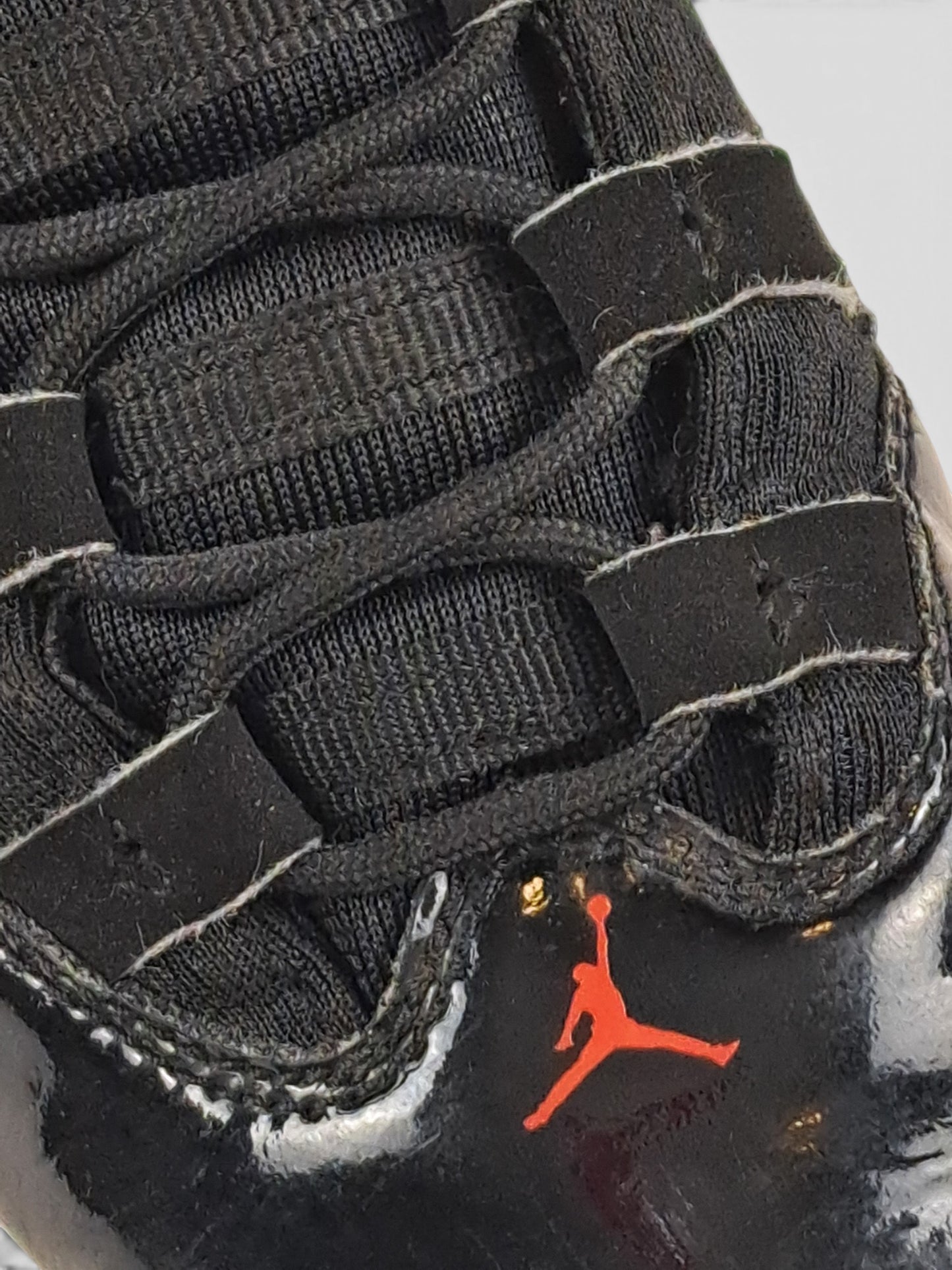 Close-up of BaraBarnet Jordan sneakers featuring black mesh, patent leather details, and a red Jumpman logo.