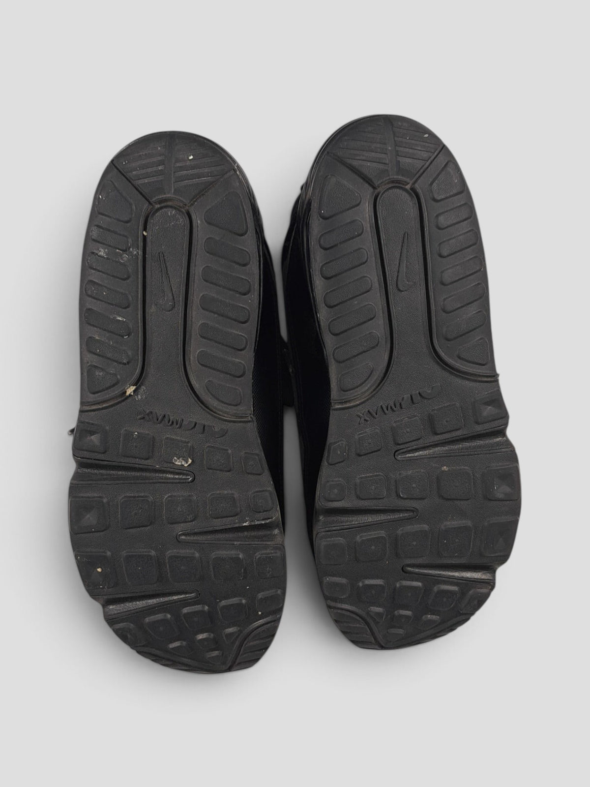 BaraBarnet Nike Air Max sneakers showing the black textured rubber outsoles from a bottom view