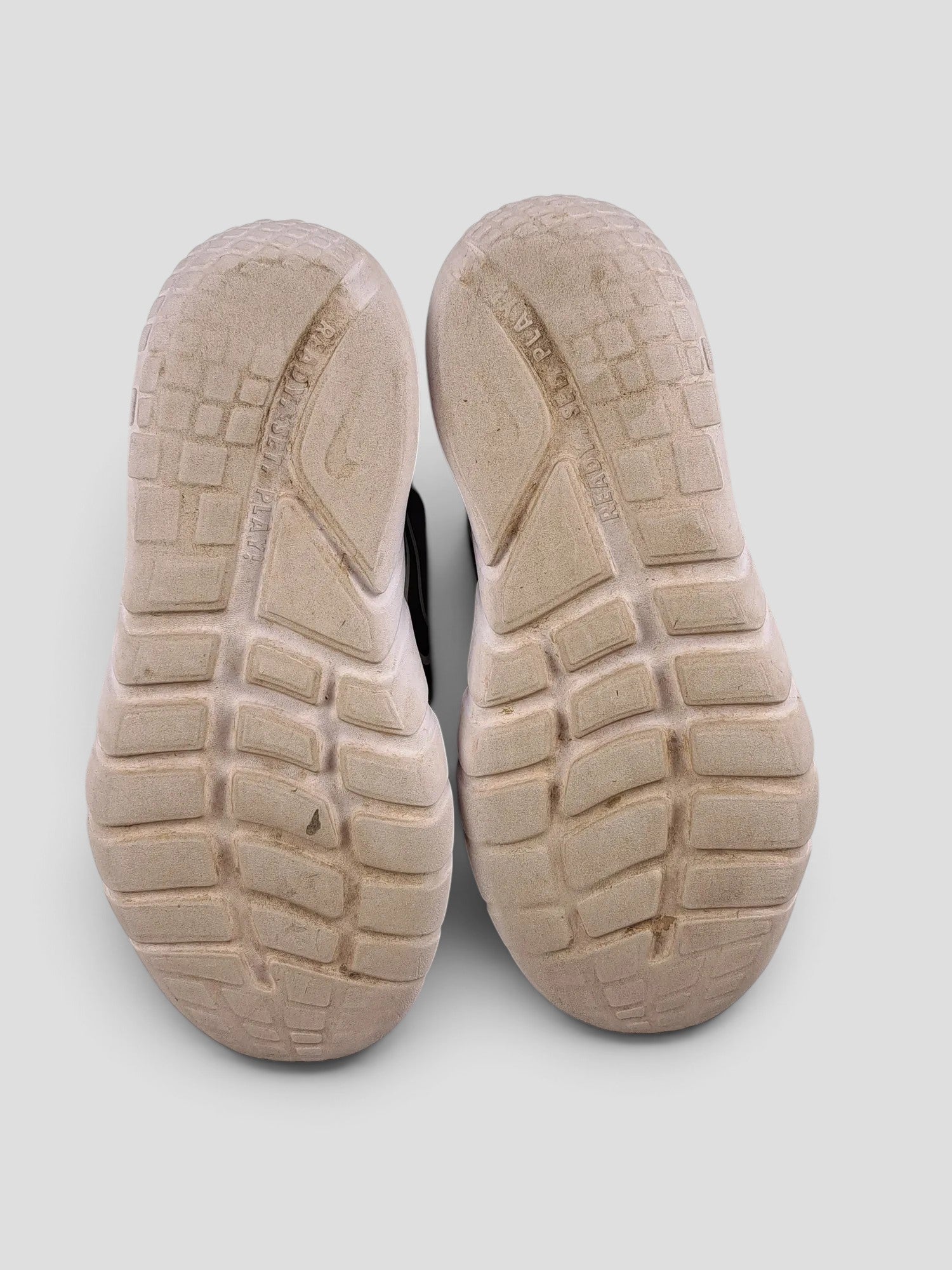 BaraBarnet Nike sneakers showing the worn white rubber outsoles with textured grip patterns