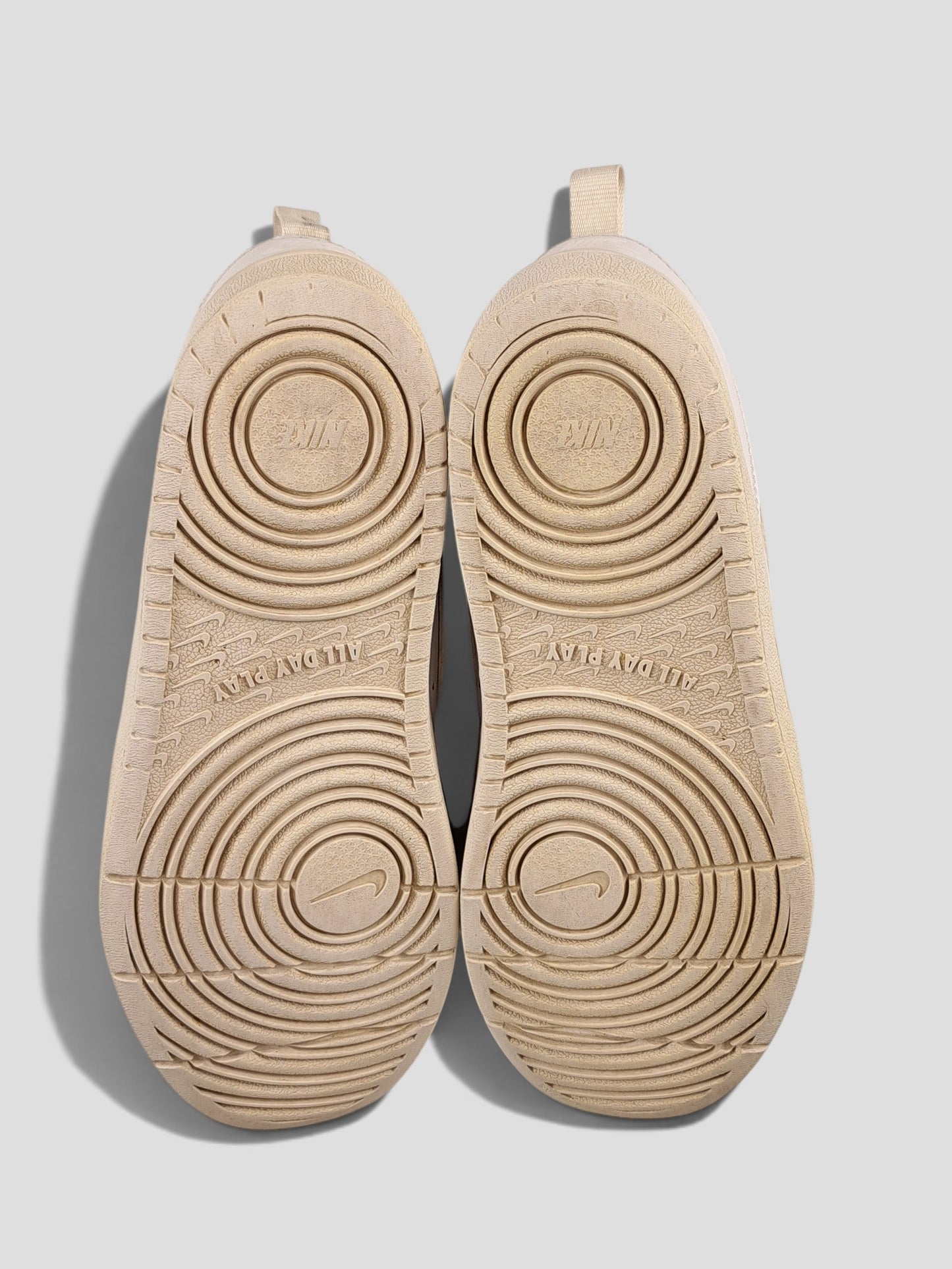 BaraBarnet Nike sneakers showing the beige rubber outsoles with circular tread patterns and All Day Play text