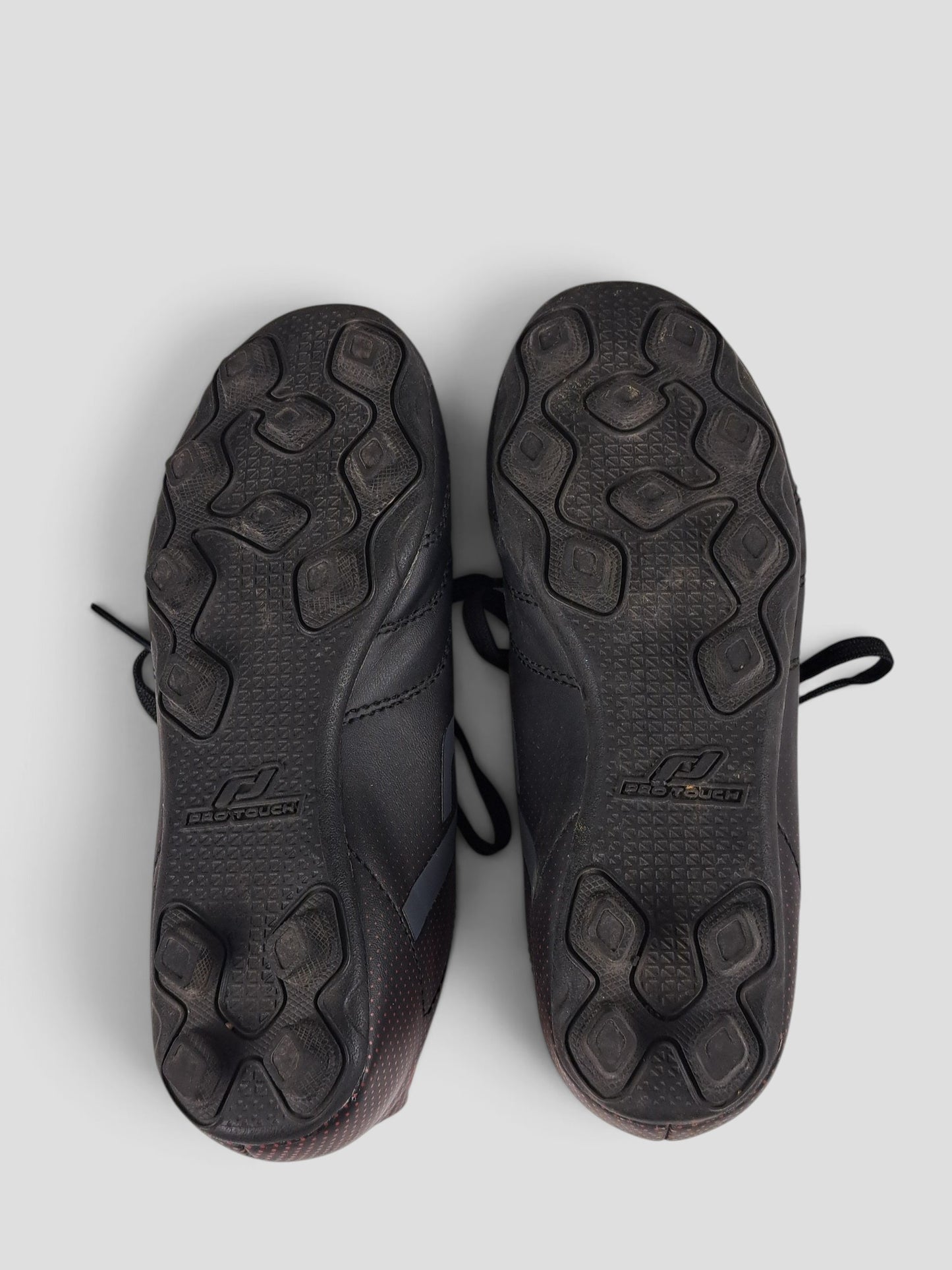 BaraBarnet ProTouch size 30 black football boots showing the textured rubber stud outsoles from a bottom view.