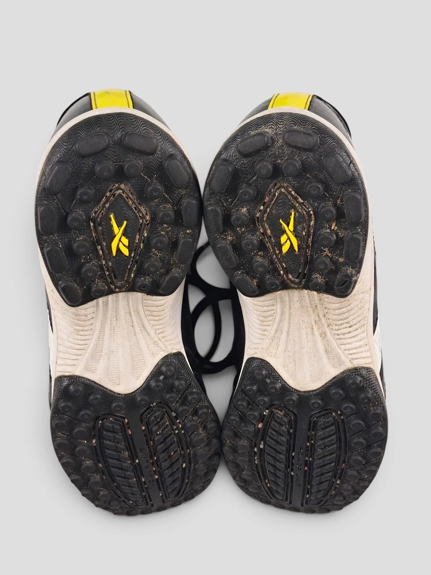 BaraBarnet Reebok sneakers showing the black and white rubber outsoles with yellow logo detailing