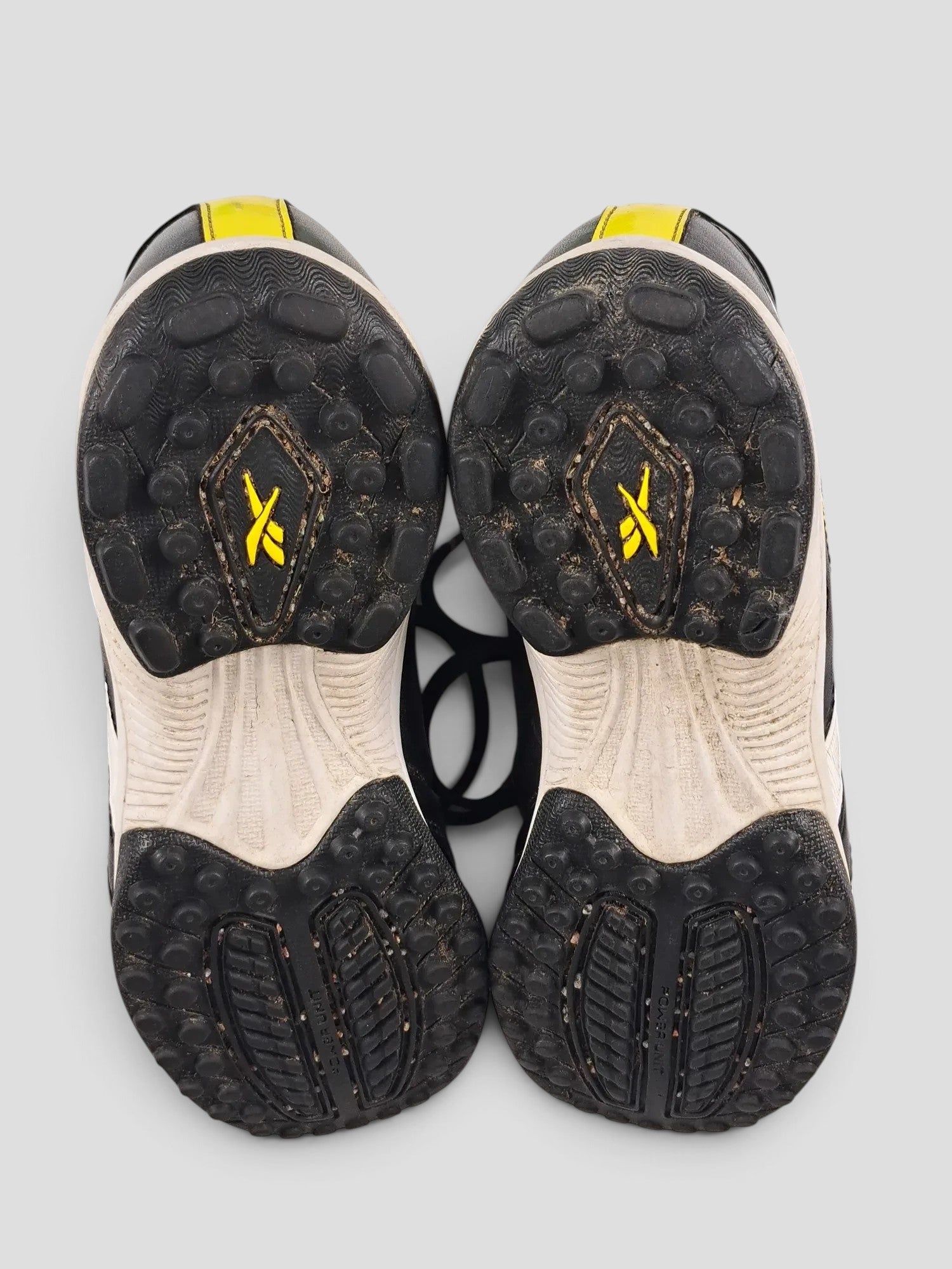 BaraBarnet Reebok sneakers showing the black and white rubber outsoles with yellow logo detailing