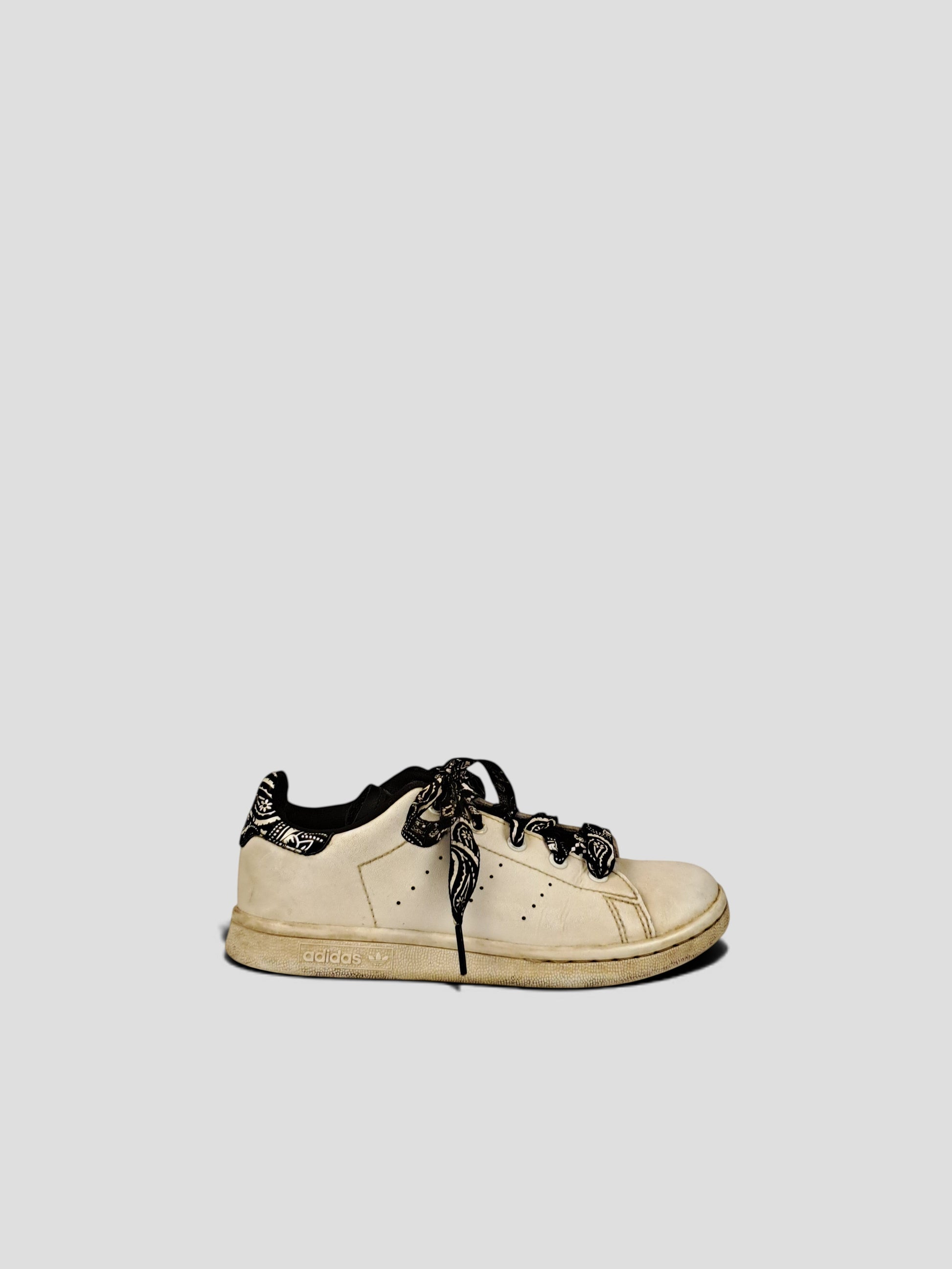 BaraBarnet white Adidas sneakers featuring black patterned laces and a matching heel tab on a neutral background.